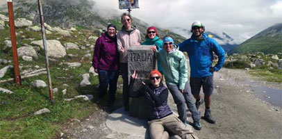 A group of hikers resting by a grey rock in the mountains near Italy