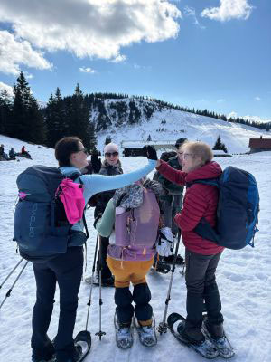 A group of women snowshoers celebrating with high fives in the mountains