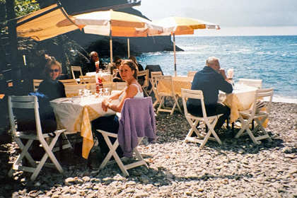 People enjoying lunch at a seaside restaurant on a pebble beach along the Italian Riviera.