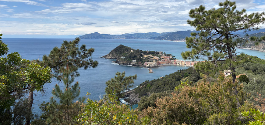 Panoramic view of the Ligurian coastline with lush green hills, turquoise sea, and the village of Sestri Levante.