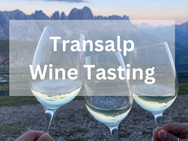 Three glasses of wine in front of a mountain range at sunset.