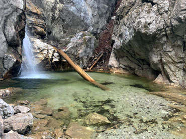 Small waterfall in a rocky gorge of the Bavarian Alps flowing into a clear turquoise pool – captured during a guided nature hike near Kochelsee.