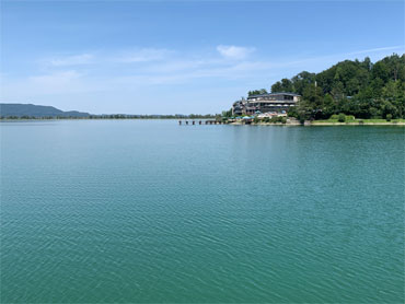 Peaceful view over Lake Kochelsee in the Bavarian Alps with turquoise water, forested shore and clear blue sky – captured during a guided nature hike near Kochelsee.
