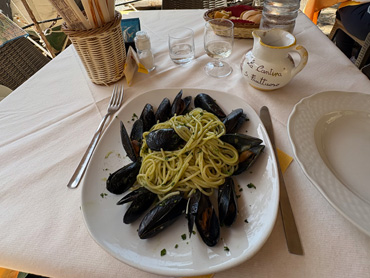 Plate of spaghetti with mussels served on a white table outdoors in Liguria, Italy
