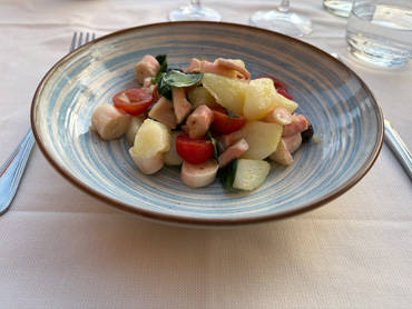 Plate of gnocchi with cherry tomatoes, zucchini, and herbs served outdoors in Liguria, Italy