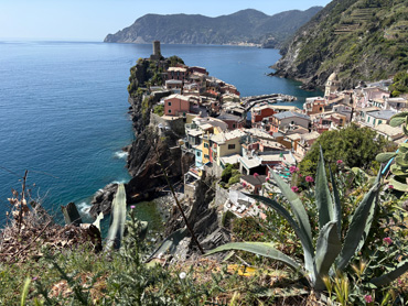 Panoramic view of Vernazza village with colorful houses, tower on rocky cliff, and blue sea in Cinque Terre, Italy