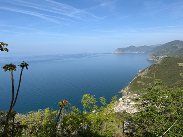 Panoramic view of Riomaggiore village and the Ligurian coastline with blue sea and green hills