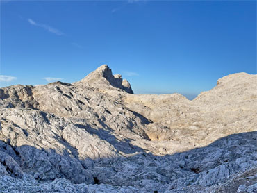 Rugged limestone landscape in Slovenia's Julian Alps with dramatic mountain peaks under a clear blue sky