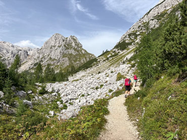 Hikers walking along an alpine trail through a rocky valley in Slovenia's Julian Alps