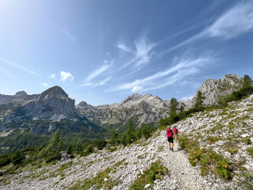 Hikers trekking along a scenic alpine trail in Slovenia's Julian Alps with panoramic mountain views