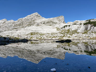 Limestone peaks reflected in a tranquil alpine lake in Slovenia's Julian Alps