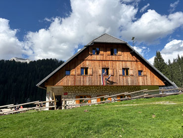 Traditional mountain hut surrounded by alpine meadows and forest in Slovenia's Julian Alps