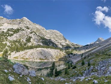 Mountain lake surrounded by rugged limestone peaks and alpine terrain in Slovenia's Julian Alps