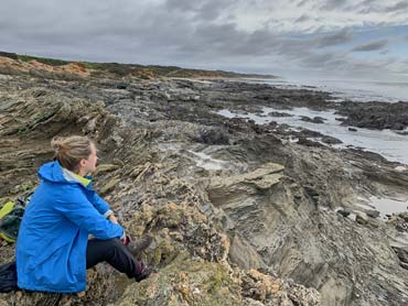 Woman sitting on rocks enjoying the view over the Ocean Rocks and cliffs in the background