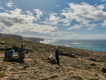 View of sandy trail with ocean and cliffs in background