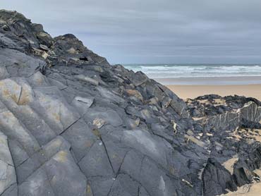 Slate rock formations on beach with ocean in background