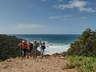 View of sandy trail with ocean and cliffs in background